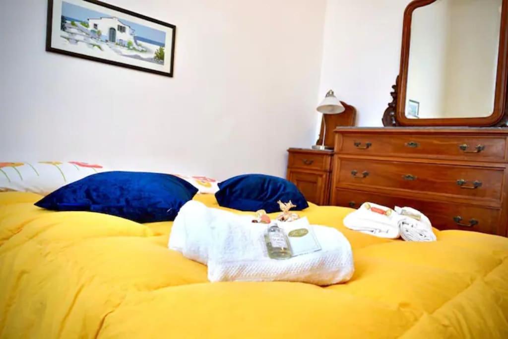een slaapkamer met een geel bed, handdoeken en een spiegel bij La casetta nella Città dei due Mari in Sestri Levante