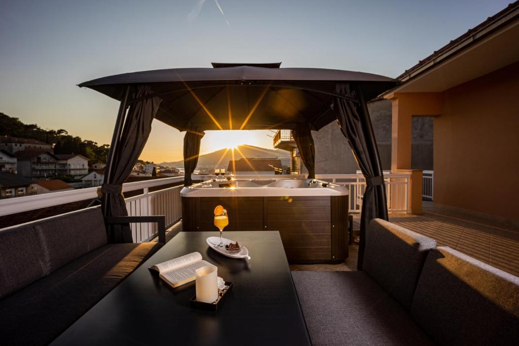 uma varanda com uma mesa e uma banheira no telhado em Beautiful Holiday Home "Villa Relax Oasis" em Trogir