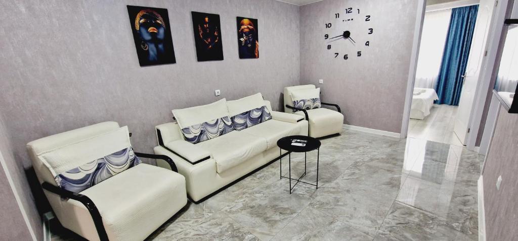 uma sala de estar com dois sofás e um relógio na parede em nest1, Новое белье, есть бесплатная парковка em Kutaisi