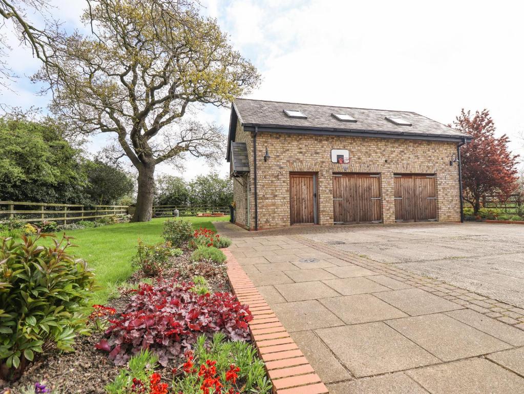 a brick building with a garage and some flowers at Barn Owl Annex in Market Rasen