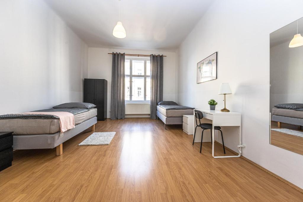 a bedroom with two beds and a desk and a table at Vltava Apartments Prague 7 in Prague