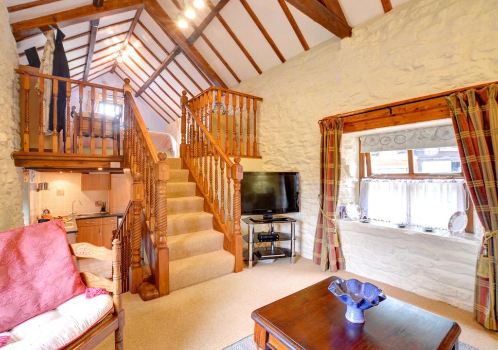 a living room with a staircase and a tv at Woodpecker Cottage in Hutton le Hole