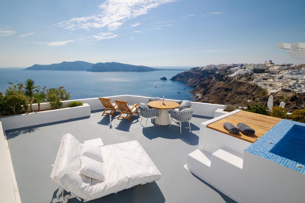 a balcony with a table and chairs and the ocean at IKIES Santorini in Oia