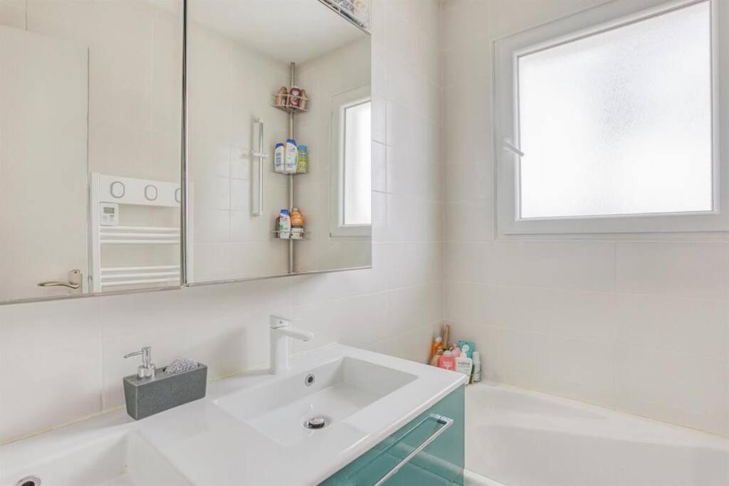 a white bathroom with a sink and a mirror at Maison de vacances Bisca in Biscarrosse