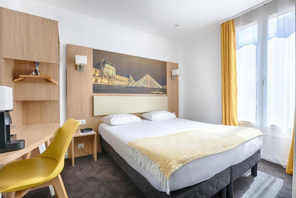 ブローニュ・ビヤンクールにあるオテル ドゥ パリの大きなベッドとデスクが備わるホテルルームです。