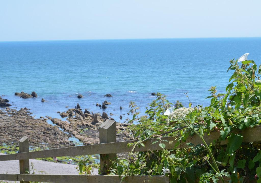 une clôture sur une plage avec l'océan dans l'établissement High Tides, à Crafthole