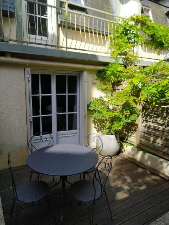 une table et des chaises assises sur une terrasse dans l'établissement Le coin vert, à Deauville