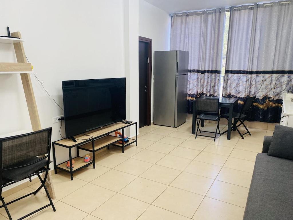 a living room with a television and a table with chairs at New! Royal family ground apartment 2BR in Bat Yam