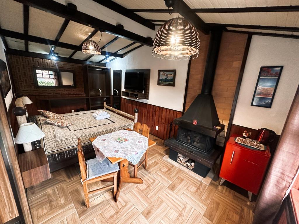 1 dormitorio con mesa, cama y chimenea en Chalé Dumont Pousadinha, en Monte Verde