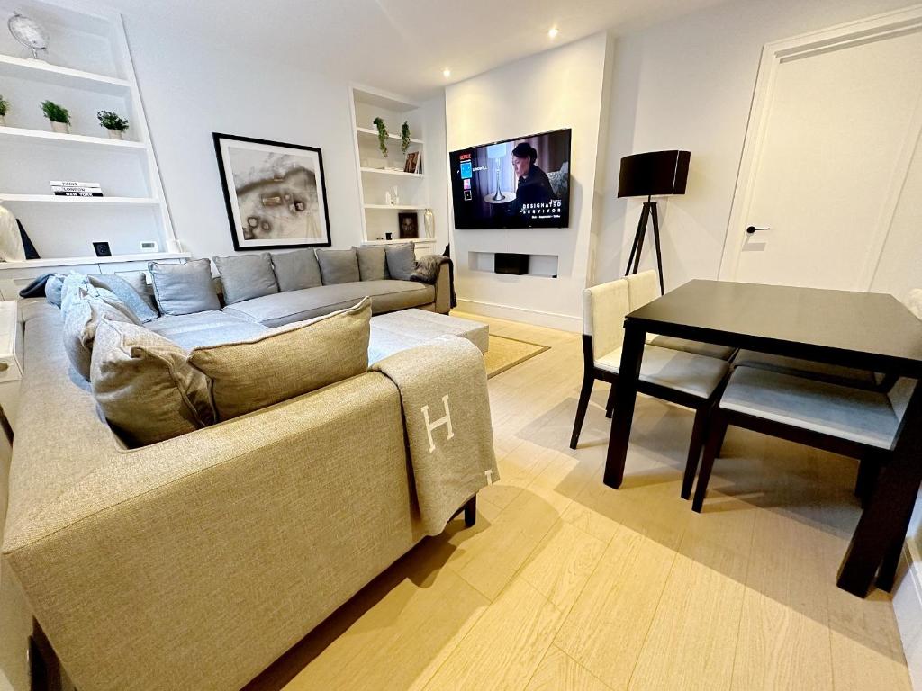 uma sala de estar com um sofá e uma mesa em Londwell, Luxe and Leaves, Chelsea Flat with Private Garden em Londres