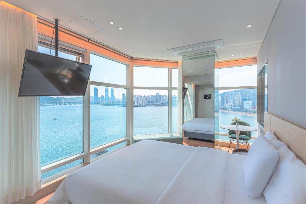 a bedroom with a large bed with a tv and windows at Hotel Marine view in Busan