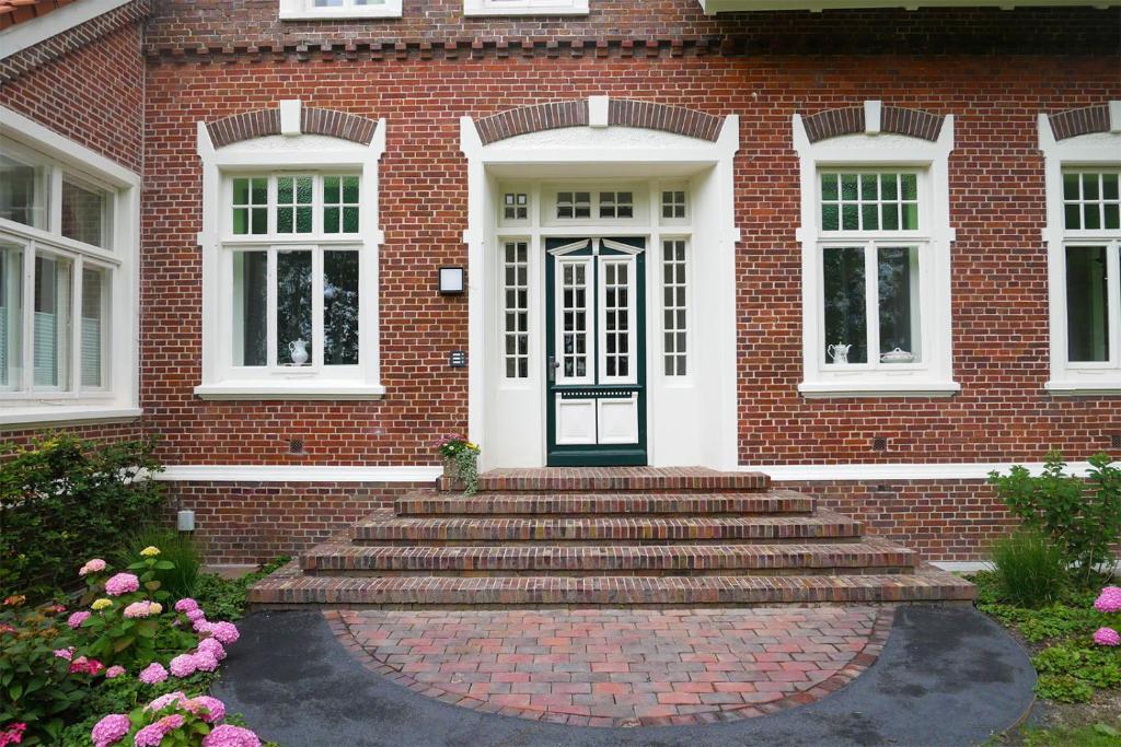 une maison en briques avec des escaliers menant à une porte dans l'établissement Gulfhof Fresena, à Norden