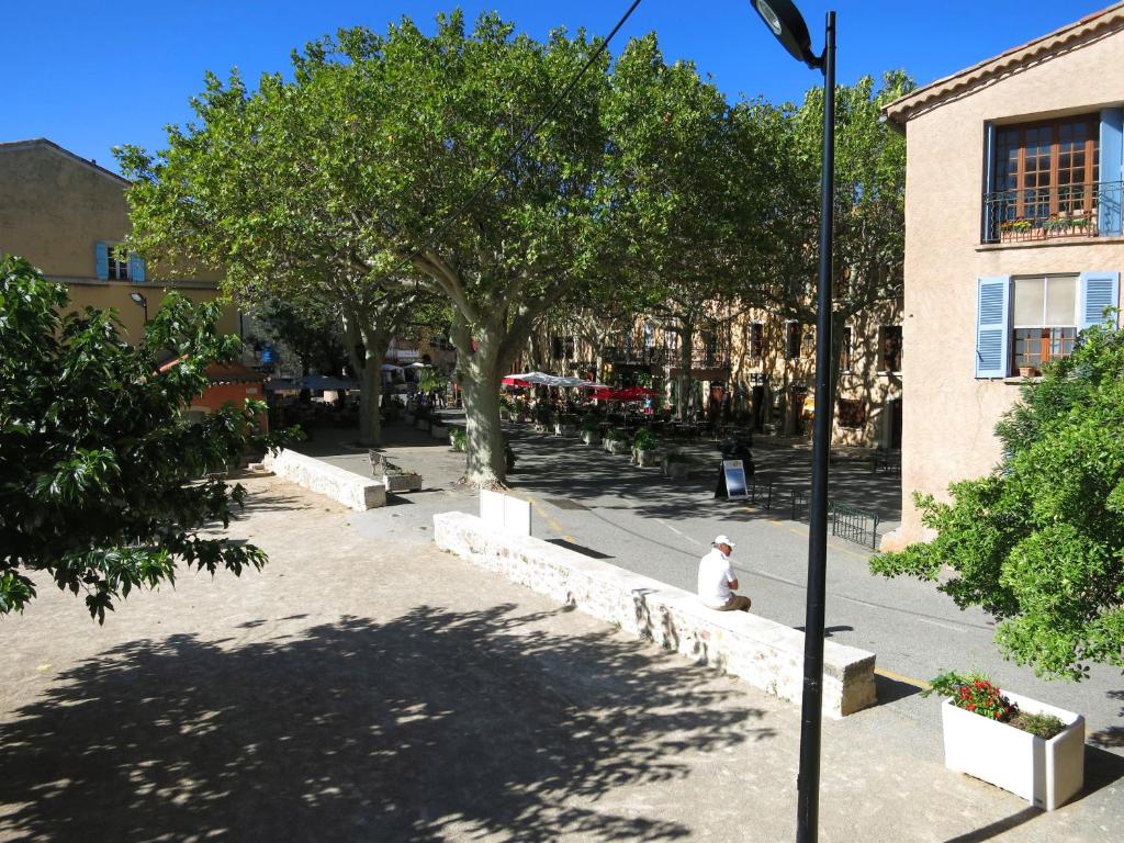 a man sitting on a bench next to a building at Apartement Victor in Tourtour