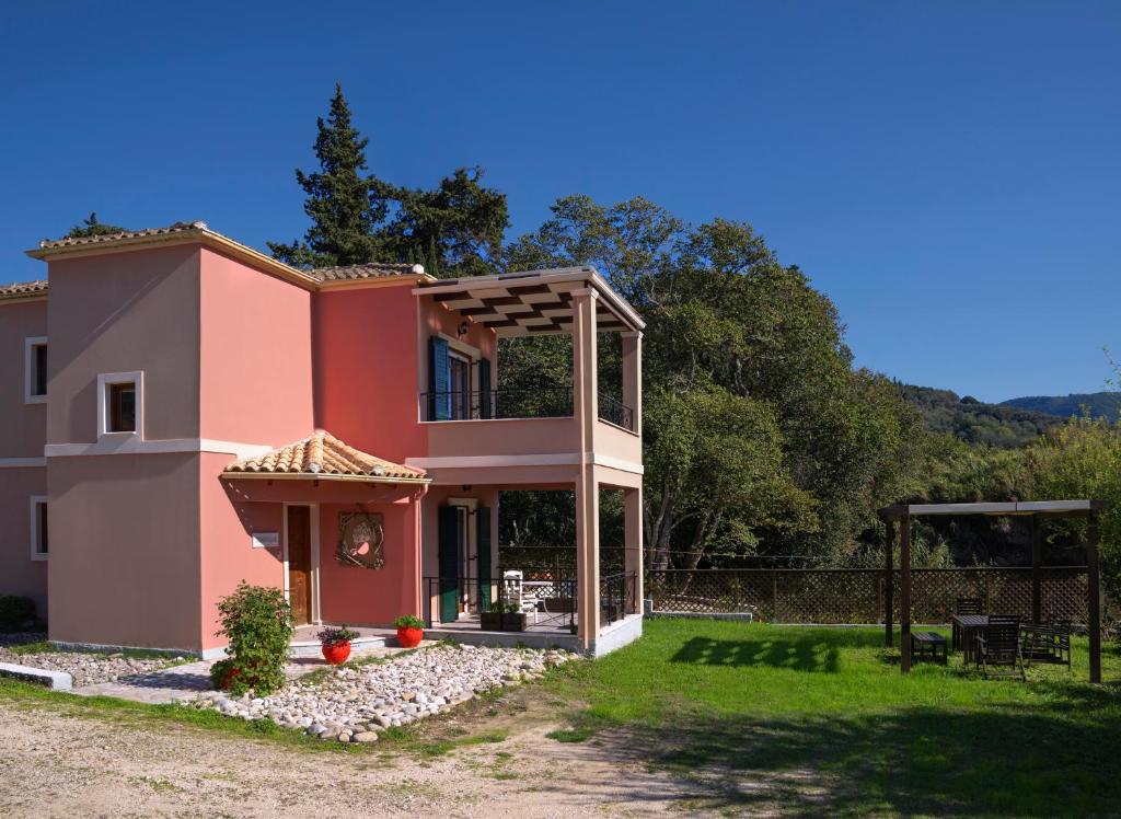 a pink house with a fence and a yard at Zen Stone House in Agios Georgios Pagon