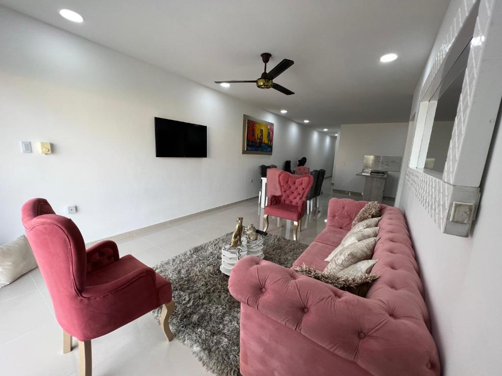 sala de estar con sofá rosa y 2 sillas en Hermoso apartamento central, en Montería