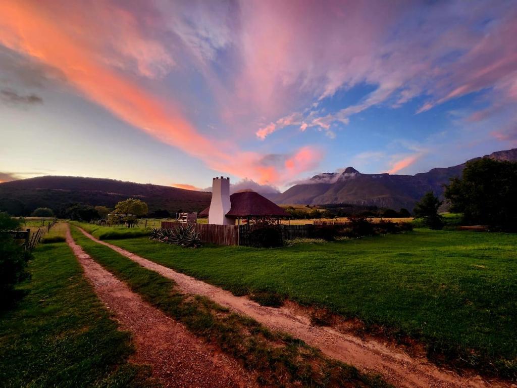 a dirt road leading to a building in a field at Hermitage Huisies in Swellendam