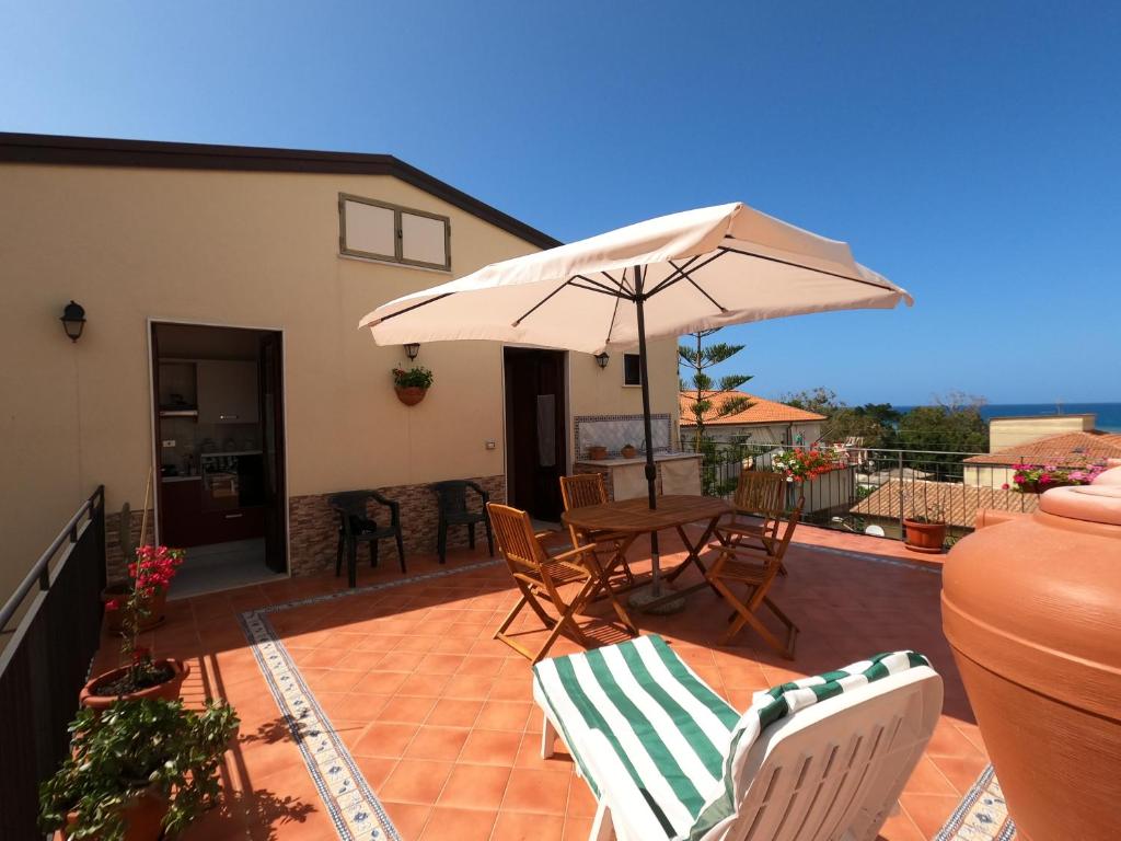 une terrasse avec une table, des chaises et un parasol dans l'établissement Terrazza Lungomare, à Caronia Marina