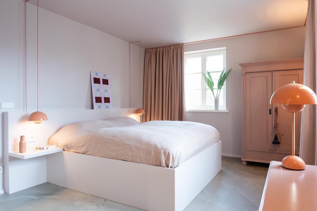 a white bedroom with a white bed and a window at St. Oberholz Woldzegarten Retreat in Leizen