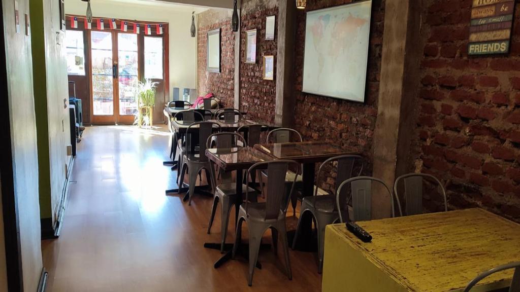 a dining room with tables and chairs and a brick wall at Aji Hostel in Santiago