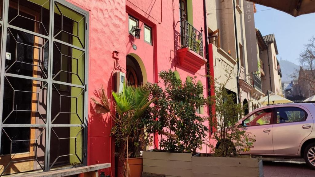 a pink building with potted plants on a street at Aji Hostel in Santiago