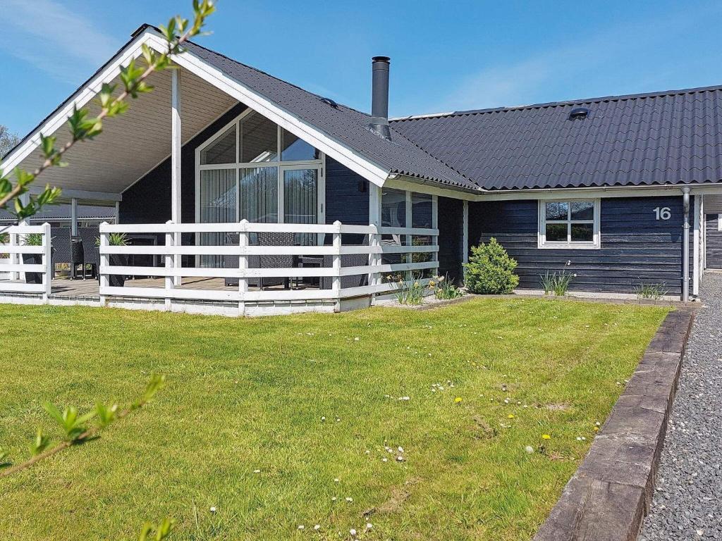 a blue house with a white fence in the yard at Three-Bedroom Holiday home in Hemmet 26 in Hemmet