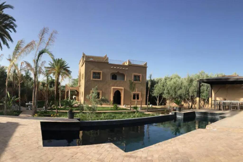 a large house with a swimming pool in front of it at Dar Lily, villa familiale avec piscine et services in Skoura