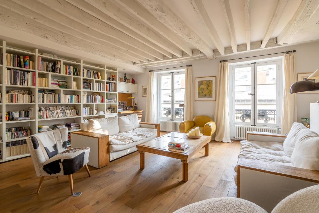 a living room with white furniture and bookshelves at Veeve - Loft Living on Luxembourg in Paris