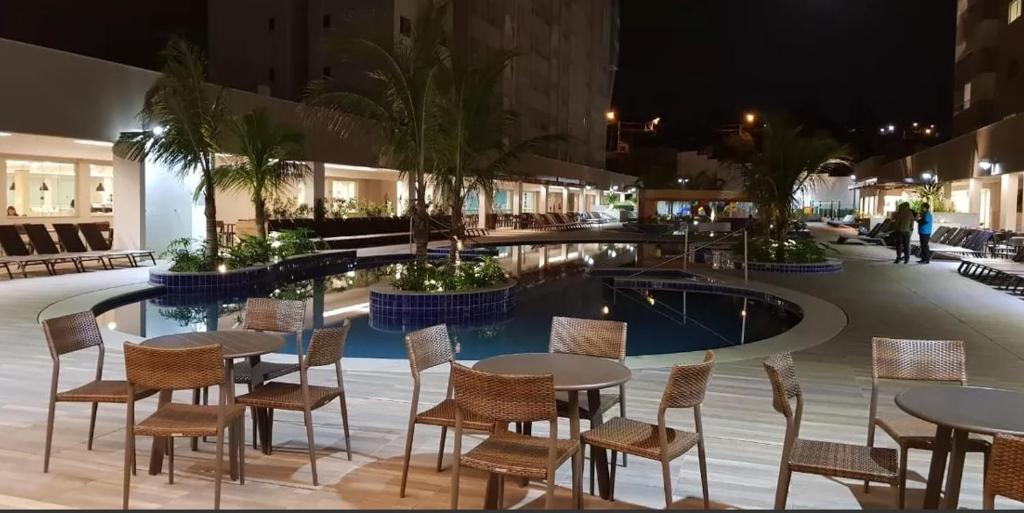 a restaurant with tables and chairs next to a pool at Apto do Veloso no Resort in Olímpia