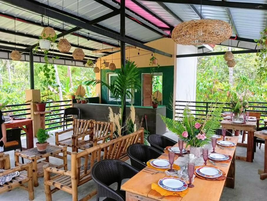 a restaurant with wooden tables and chairs and plants at Klub Safari Inn & Lounge in Tagbina