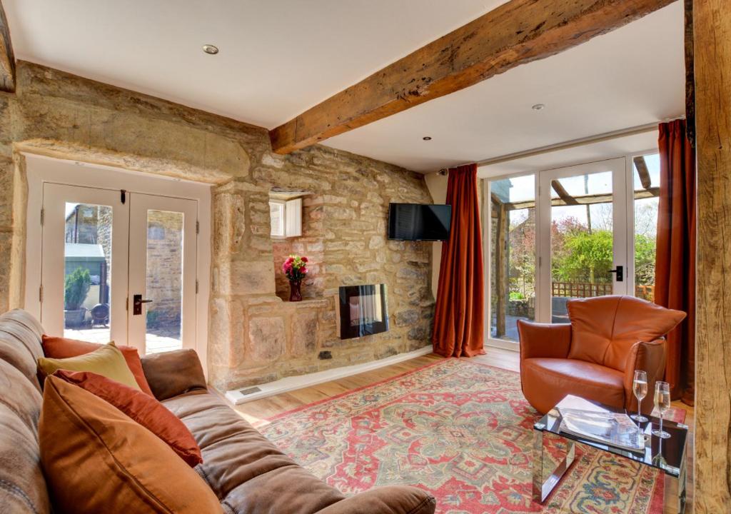 een woonkamer met een bank en een tv bij TLasses Cottage in Kildwick