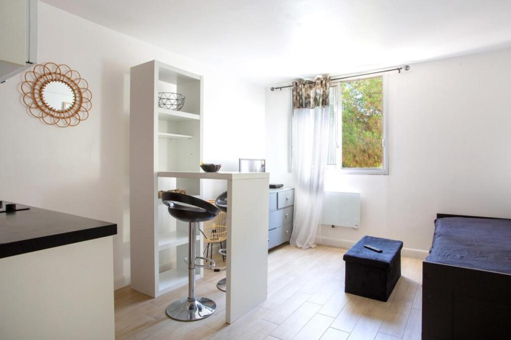 une cuisine blanche avec un tabouret de bar et une fenêtre dans l'établissement Charmant Studio avec parking, à Nice