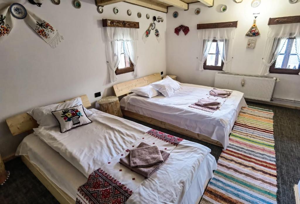 a bedroom with two beds and a rug at Căsuța lui Gogu in Borsa