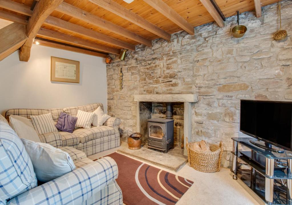 a living room with a stone wall at Thornsgill Cottage in Askrigg