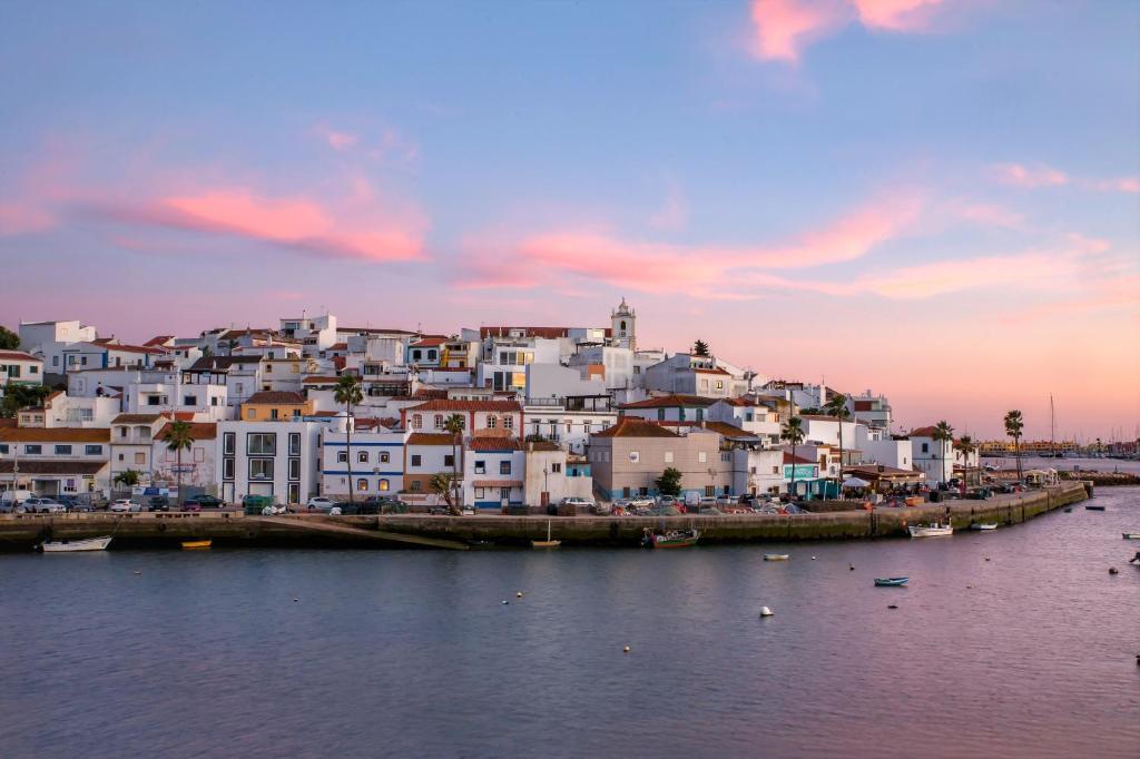 a group of white houses on a hill next to the water at Hotel Rural Brícia Du Mar in Ferragudo
