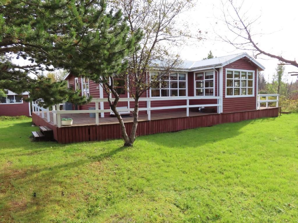 a large red house with a tree in the yard at Red Riding Hood Cabin On the Golden Circle Next to Kerið in Selfoss