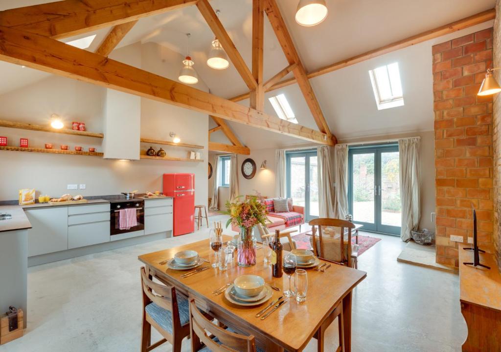 a kitchen and living room with a wooden table and chairs at The Stables at The Foldyard in Holme upon Spalding Moor