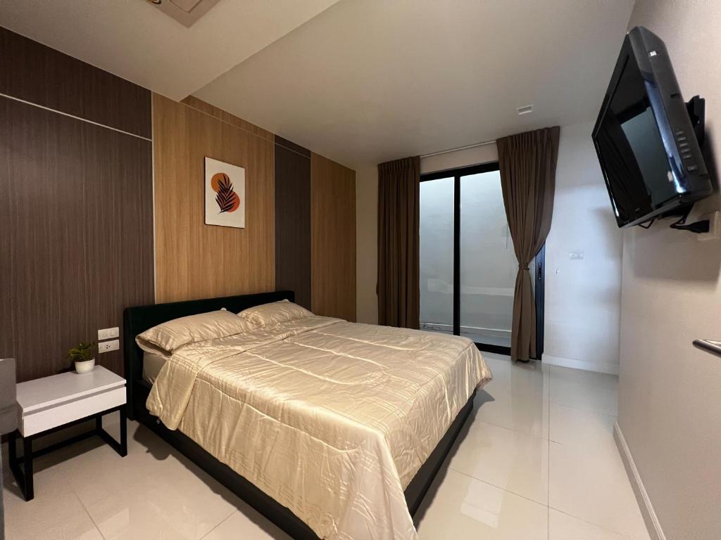 a bedroom with a bed and a flat screen tv at Smile Residence at Kaset-Sena in Ban Yang