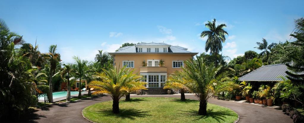 une grande maison avec des palmiers en face de celle-ci dans l'établissement Maison D’hôtes Coignet, à Beau Bassin-Rose Hill