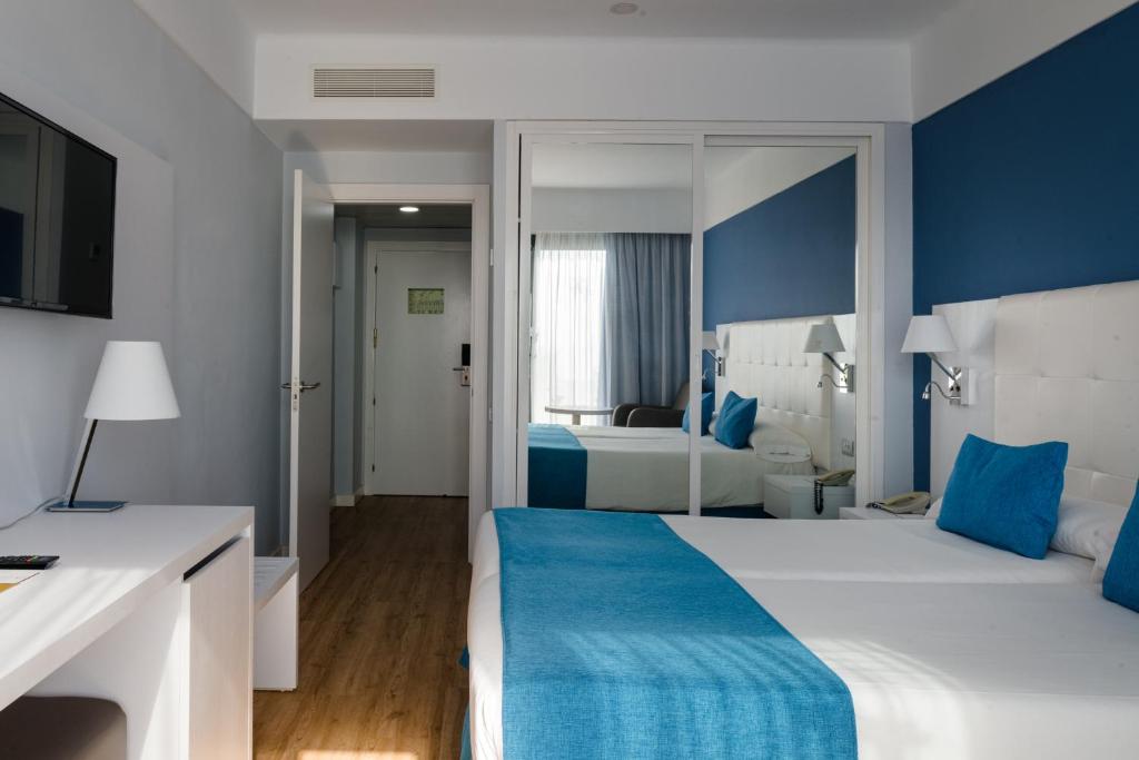 a hotel room with a large bed with blue accents at Alexandre Grand Teguise Playa in Costa Teguise
