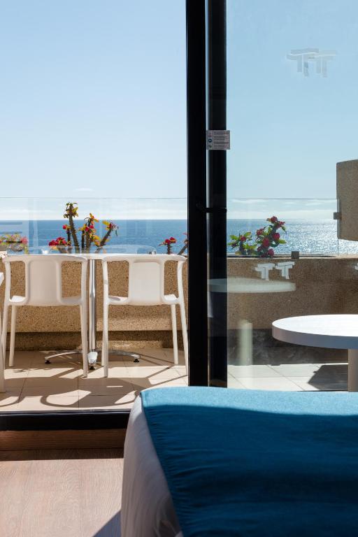a room with a view of the ocean with a table and chairs at Alexandre Grand Teguise Playa in Costa Teguise