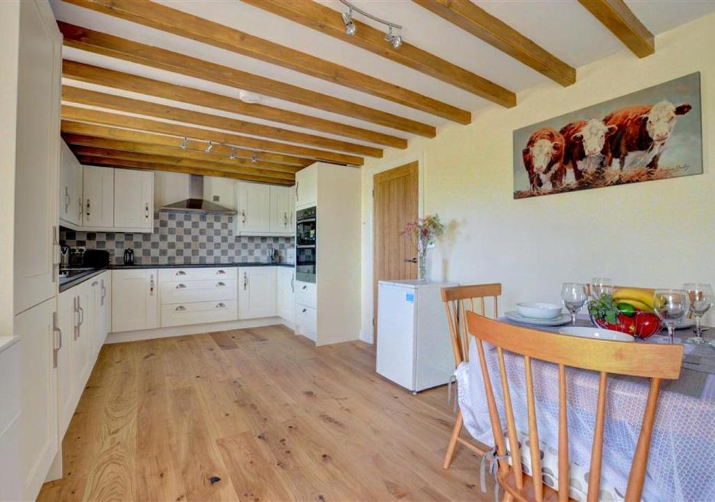 a kitchen with white cabinets and a table with chairs at The Old Cow Byre in Lealholm