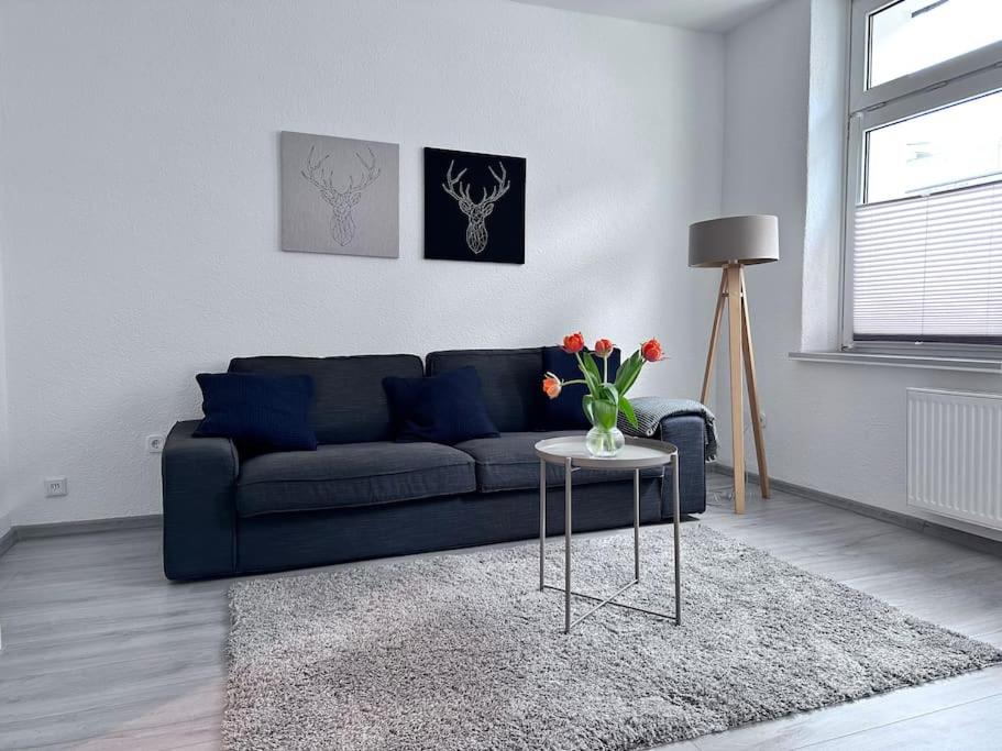 a living room with a blue couch and a table with flowers at Möblierte EG- Wohnung zentral in Herne mit Parkplatz,WLAN und Netflix in Herne