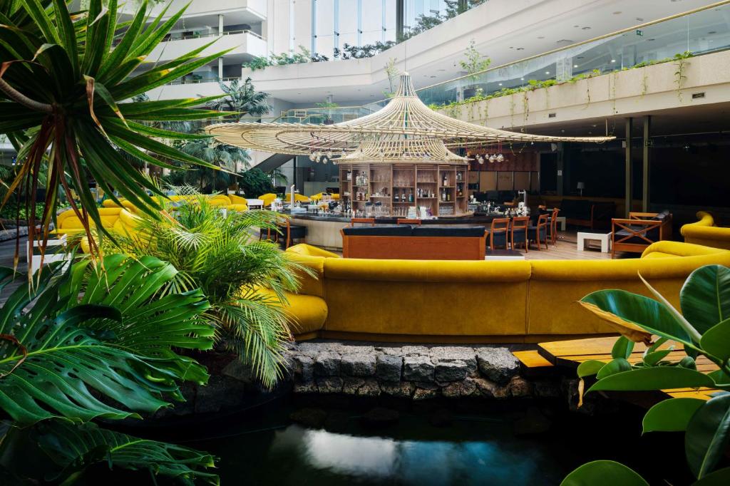 a hotel lobby with a yellow couch and a bar at Alexandre Grand Teguise Playa in Costa Teguise