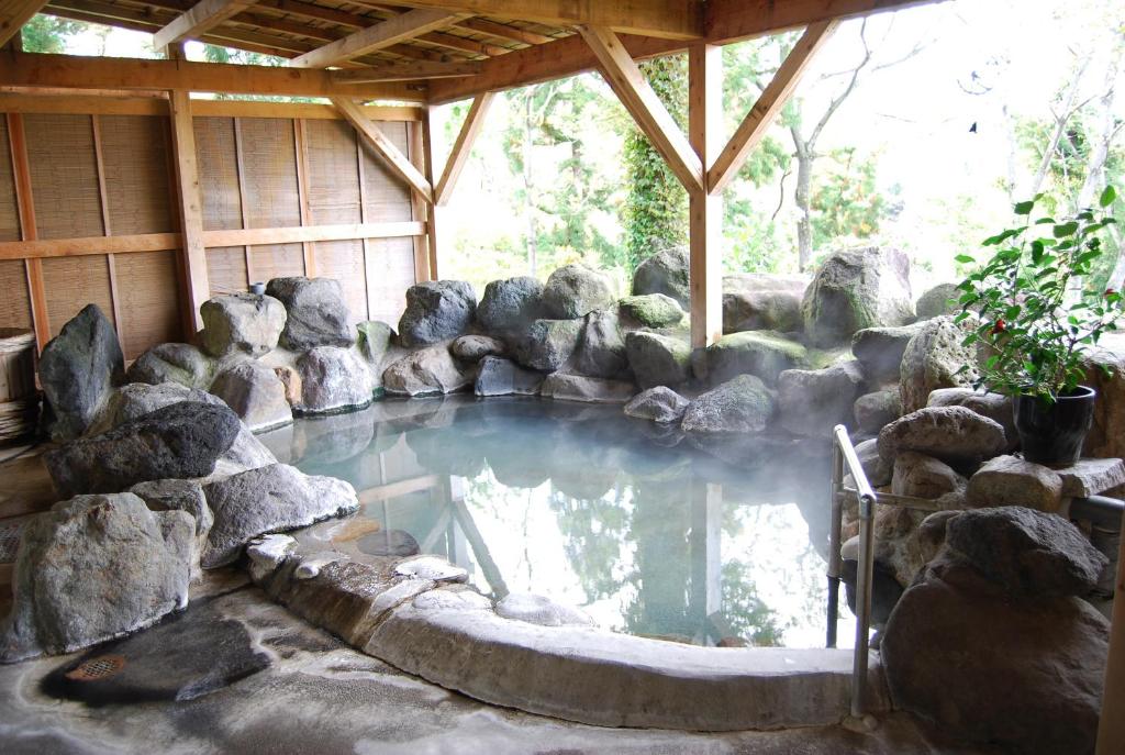 une piscine d'eau dans une pièce avec des rochers dans l'établissement Kogakuro, à Myōkō