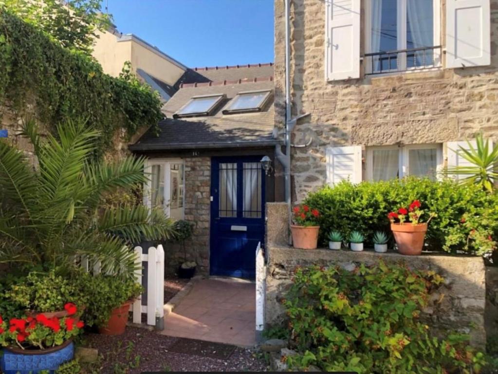 a house with a blue door and some plants at Maison bord de mer 10 couchages in Saint-Vaast-la-Hougue