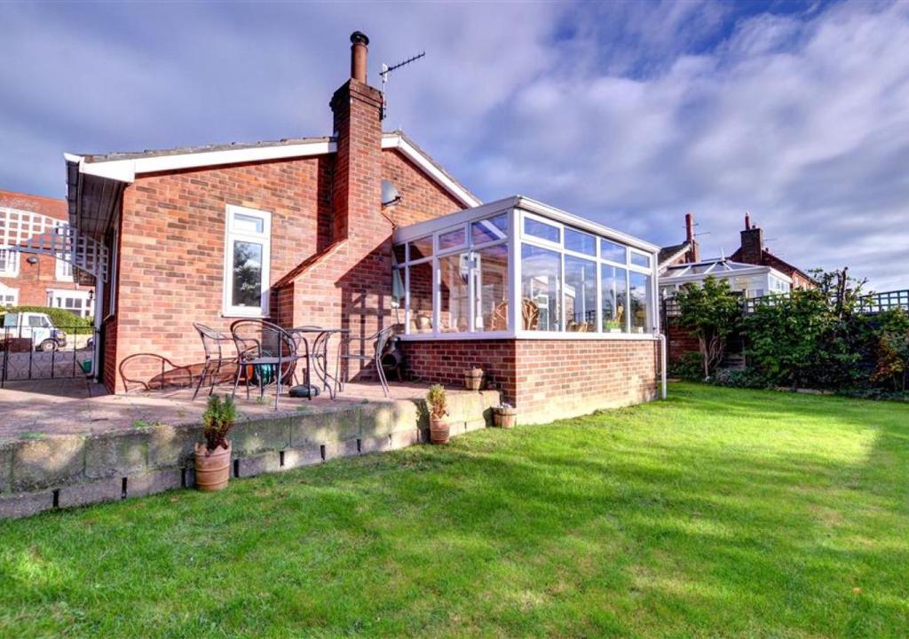 a brick house with a conservatory on a lawn at The Nook in Robin Hood's Bay