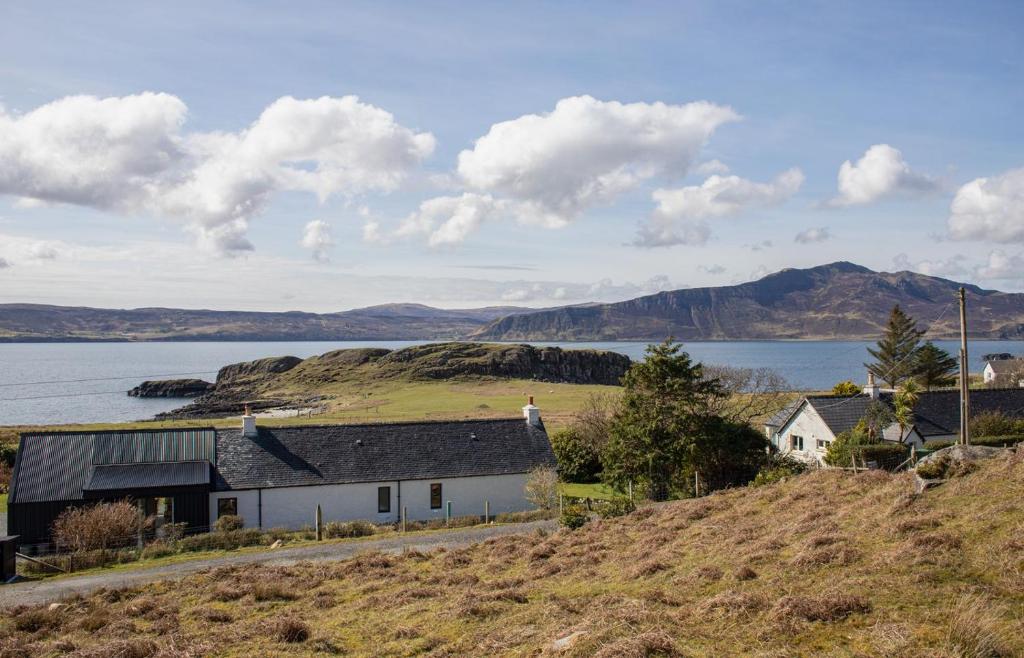 a house on a hill next to a body of water at No 6 Oskaig in Raasay