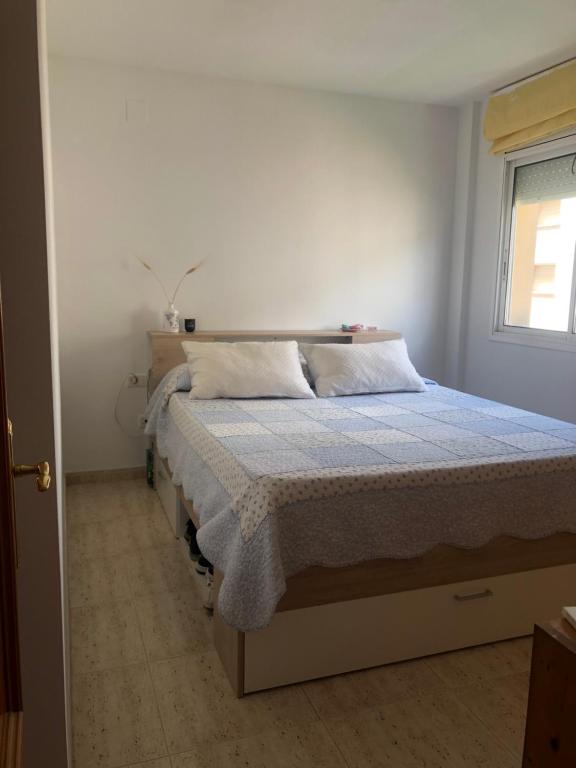 1 dormitorio con 1 cama con edredón azul y ventana en Apartamento a 20 metros de la playa, en Calafell