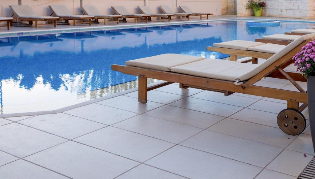 a pool with chaise lounge chairs next to a swimming pool at Aspasias Luxury Suite in Chania
