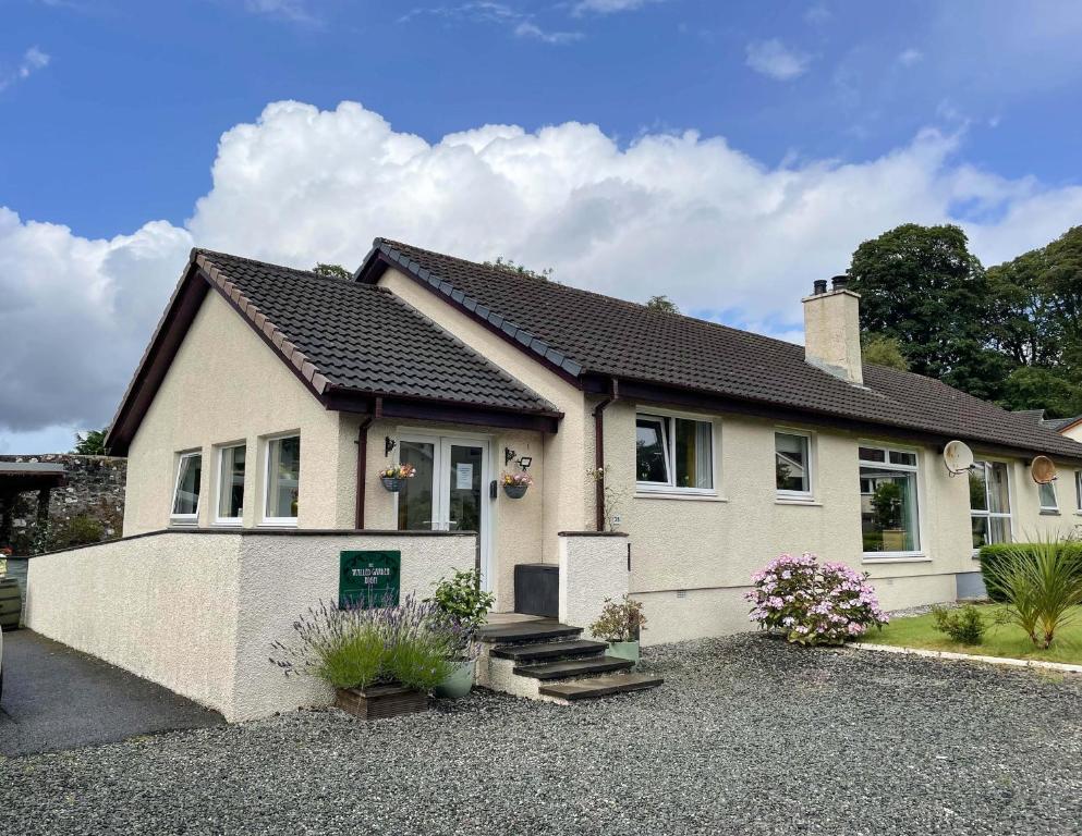 a house with a gravel driveway in front of it at Pebble Cottage in Portree